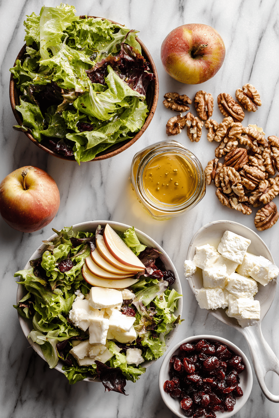 Fresh ingredients for apple and walnut salad with crisp Honeycrisp apples, toasted walnuts, greens, cheese, and tangy vinaigrette.
