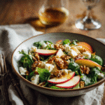 Pouring cider vinaigrette over apple and walnut salad with fresh greens, apples, and toasted walnuts.