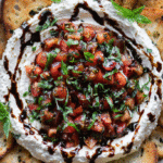 Bruschetta Dip topped with tomatoes, basil, and balsamic glaze served with toasted baguette slices
